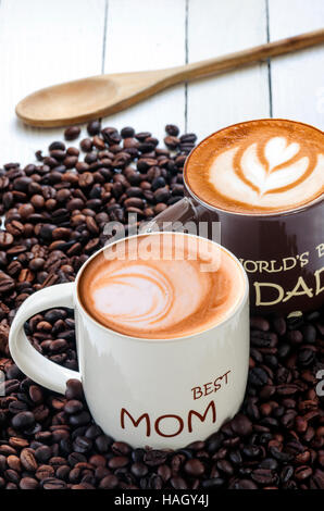 Zwei Tassen Kaffee (weiß und braun) mit Kaffeebohnen auf hölzernen Hintergrund. Stockfoto