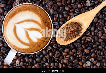 Weiße Tasse Kaffee, Latte Art und Kristallzucker in Kaffeebohnen Hintergrund Stockfoto