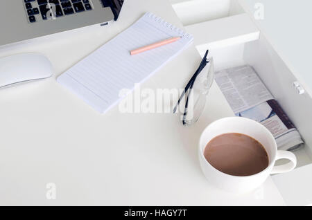 Tasse Kaffee, leere Notiz mit Bleistift und Laptop auf weißen Tisch. Stockfoto