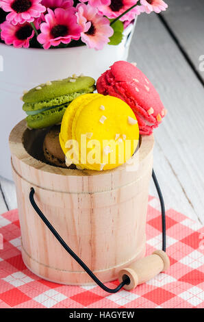Süße und bunte französische Macarons oder Macaron in kleinen hölzernen Tank auf hölzernen Hintergrund, Dessert. Stockfoto