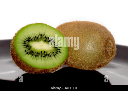 Ein und eine halbe Kiwi auf der schwarzen Platte Stockfoto