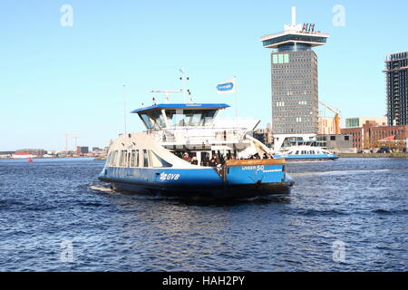 Fußgänger und Fahrrad Fähre überqueren Fluss IJ in Amsterdam, goede Turm im Hintergrund. Stockfoto