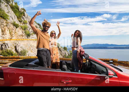 Gruppe von glückliche junge Menschen winken von der roten Cabrio. Stockfoto