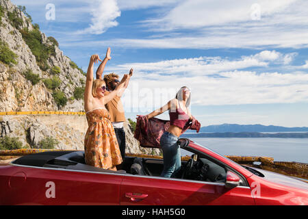 Gruppe von glückliche junge Menschen winken von der roten Cabrio. Stockfoto