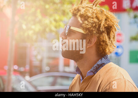 Porträt von junger schwarzer Mann mit Dread Locks mit Sonnenbrille. Sonne-Effekt angewendet. Stockfoto