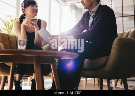 Schuss der Geschäftsmann zeigen etwas auf digital-Tablette, seine Kollegin. Business-Leute treffen im Büro Lobby. Stockfoto