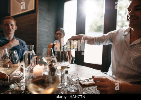 Gruppe von Freunden genießen Sie eine Mahlzeit mit Wein in einem Restaurant. Glücklich Jüngling Gläser Wein herein. Stockfoto