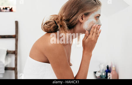 Richtungskontrolle Blick der jungen Frau, die Anwendung von kosmetischen Gesichtsmaske im Badezimmer.  Frauen die Pflege ihrer Gesichtshaut. Stockfoto