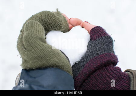 Paare-Hände halten einen herzförmigen Schneeball Stockfoto