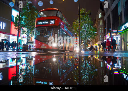 LONDON - 16. November 2016: Roten Doppeldecker-Bus spiegelt mit Lichtern Urlaub mit Käufern auf der Oxford Street. Stockfoto