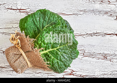 Rohe organische Wirsing Blätter auf weißem rustikalen hölzernen Hintergrund. Draufsicht mit Textfreiraum Stockfoto