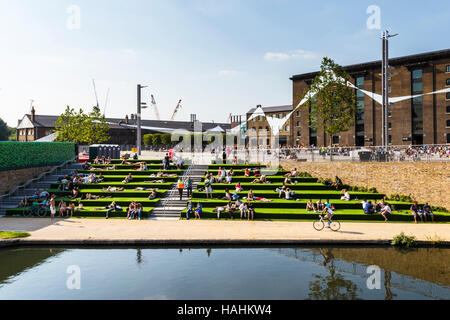 Sonnenanbeter auf der künstlichen - begrünt Schritte der Getreidespeicher Square von Regent's Canal während der Sanierung von King's Cross, London, UK Stockfoto