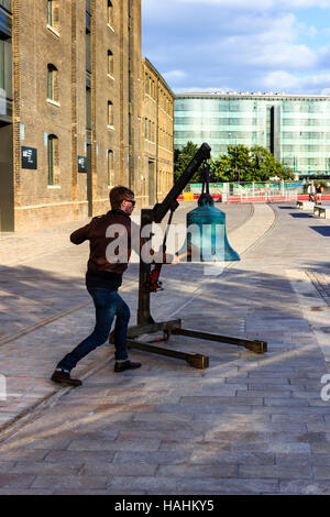 Eine große grüne Glocke geläutet wird von einem Mann in Sonnenbrille als Teil von 'Meltdown', ein Dance Umbrella Leistung in der Kornkammer Square, King's Cross, London, UK Stockfoto