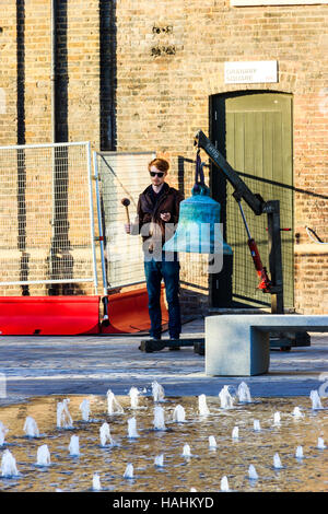 Eine große grüne Glocke geläutet wird von einem Mann in Sonnenbrille als Teil von 'Meltdown', ein Dance Umbrella Leistung in der Kornkammer Square, King's Cross, London, UK Stockfoto