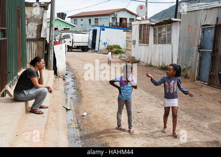 zwei Kinder im Gespräch mit einem Erwachsenen auf der Straße, Township Imizamo Yethu, Cape Town, Südafrika Stockfoto