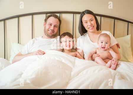 Junge Mischlinge chinesische und kaukasischen jungen Verlegung In mit ihrem Vater und Mutter Bett. Stockfoto