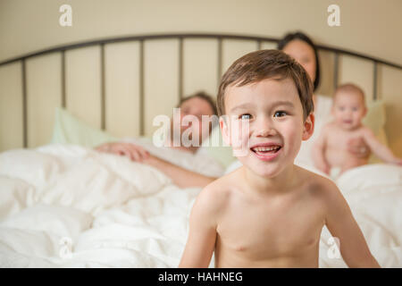 Junge gemischte Rennen Chinesisch und kaukasischen junge im Bett mit seiner Familie. Stockfoto