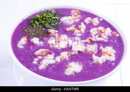 Lila Kartoffelsuppe mit Garnelen und Kräutern Stockfoto