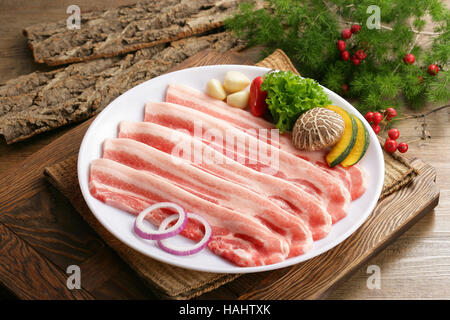 Frisch geschnittenes Schweinefleisch mit Pilzen und Salat auf Holzbrett Stockfoto