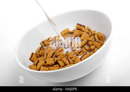 Milch in eine Schüssel mit köstlichen Mais Schokolade Kissen gießen Stockfoto
