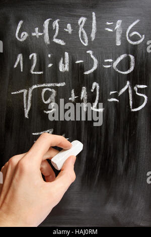 Hand schreibt mathematische Gleichungen auf schwarze Tafel Stockfoto