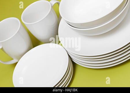 saubere Platten Schalen und Tassen am grünen Tisch Stockfoto