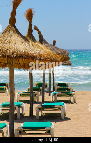 liegen und Stroh Sonnenschirme am Strand Stockfoto