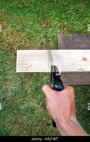 Sägen von Plank auf einem grünen Rasen-Hintergrund Stockfoto
