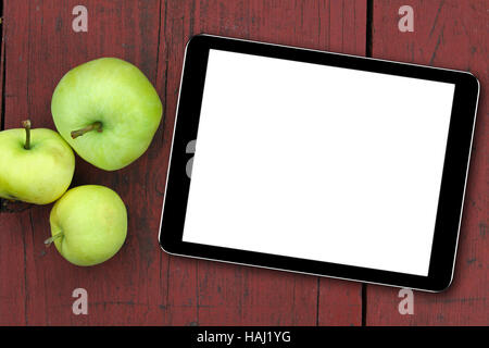 leere Tablet und Äpfel auf dem roten Holztisch Stockfoto