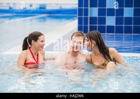 Lächelnde Menschen mit Handy im Schwimmbad machen Anruf. Gesundheit, Entspannung und Kommunikation Konzept Stockfoto