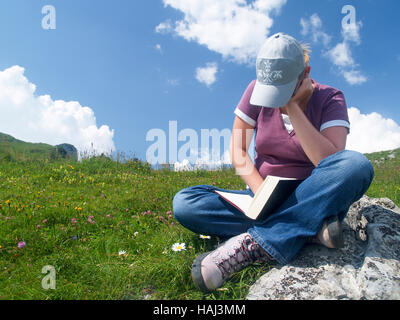 Junge Frau, die ein Buch in einer alpinen Umgebung. Stockfoto