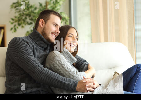 Liebevolle paar Trikot tragen ausruhen und im freien Blick durch ein Fenster sitzen auf einer Couch im Wohnzimmer zu Hause Stockfoto