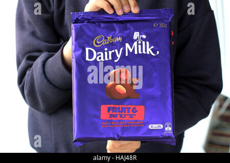 Nahaufnahme eines männlichen Kinderhand mit Cadbury Schokolade Obst- und Nussbäumen bar Stockfoto