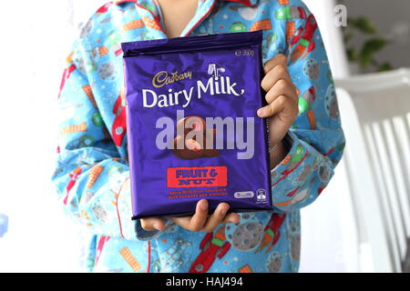 Nahaufnahme eines männlichen Kinderhand mit Cadbury Schokolade Obst- und Nussbäumen bar Stockfoto