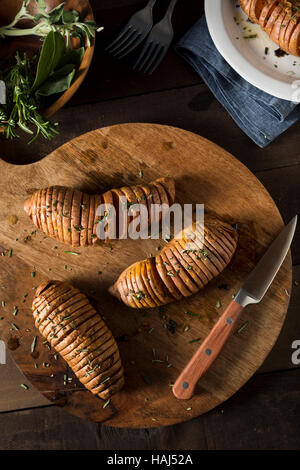 Hausgemachte Bio Hasselback Süßkartoffel mit frischen Kräutern Stockfoto