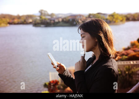 Frau mit Kreditkarte und Handy am See, Online-shopping, Internet banking Konzept, Muskelaufbau Stockfoto