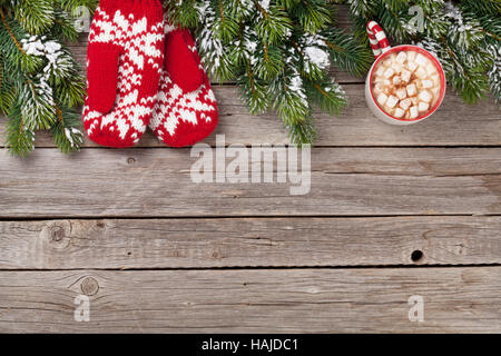 Weihnachten Hintergrund mit Tanne, Fäustlinge, heiße Schokolade und Marshmallow am Holztisch. Draufsicht mit Textfreiraum Stockfoto