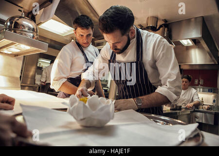 Joni Francisco, Chef de Partie, bereitet eine Gericht während Tom Brown, Senior Souschef, blickt auf, während mittags im Restaurant. Die Küche des G Stockfoto