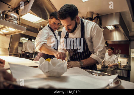 Joni Francisco, Chef de Partie, bereitet eine Gericht während Tom Brown, Senior Souschef, blickt auf, während mittags im Restaurant. Die Küche des G Stockfoto