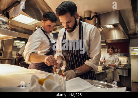 Joni Francisco, Chef de Partie, bereitet eine Gericht während Tom Brown, Senior Souschef, blickt auf, während mittags im Restaurant. Die Küche des G Stockfoto