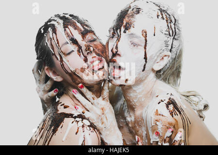 zwei Mädchen mit weißer und dunkler Schokolade übergossen. leidenschaftliche Frauen Stockfoto