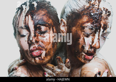 zwei Mädchen mit weißer und dunkler Schokolade übergossen. leidenschaftliche Frauen Stockfoto