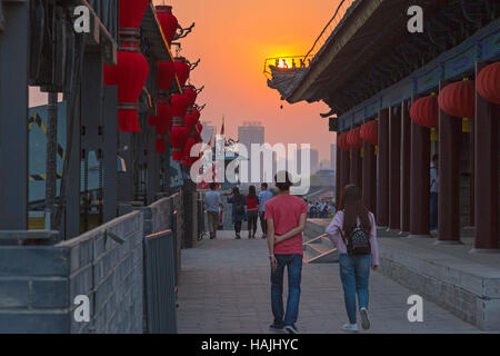 Touristen und Gebäude auf Xian Stadtmauer bei Sonnenuntergang, Provinz Shaanxi, China Stockfoto