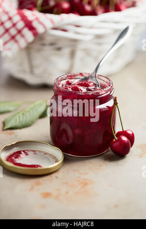 Kirschmarmelade in einem Glas mit frischen Kirschen daneben Stockfoto