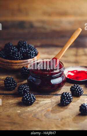 Frische hausgemachte Brombeermarmelade in Glas auf einem hölzernen Hintergrund Stockfoto