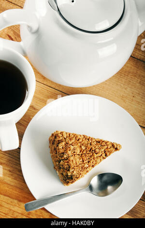 Stück Kuchen und eine Tasse Kaffee auf Holztisch Stockfoto