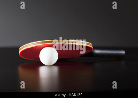 Ping-Pong-Schläger und Ball auf dunklen Tisch Stockfoto