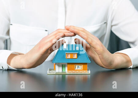 Immobilien-Versicherungen-Konzept - Hände Menschen retten kleines Haus Stockfoto