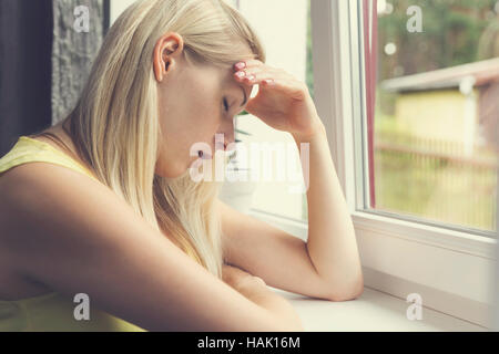 müde, deprimiert Frau am Fenster sitzen Stockfoto