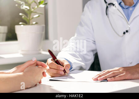 ärztliche Beratung - Arzt und Patient sitzen am Tisch Stockfoto